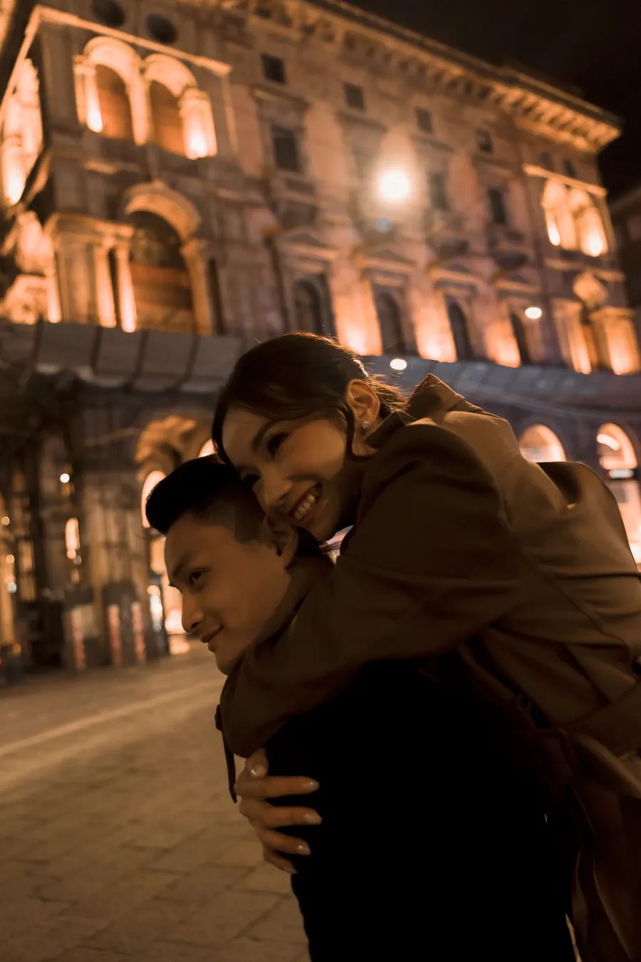 Karin riding piggyback on Matthew on a lamplit street at night